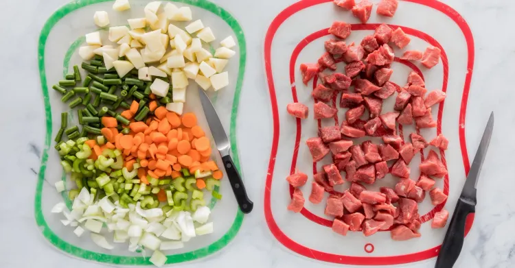Separated prep containers holding fresh chopped vegetables and raw meat to prevent cross-contamination.