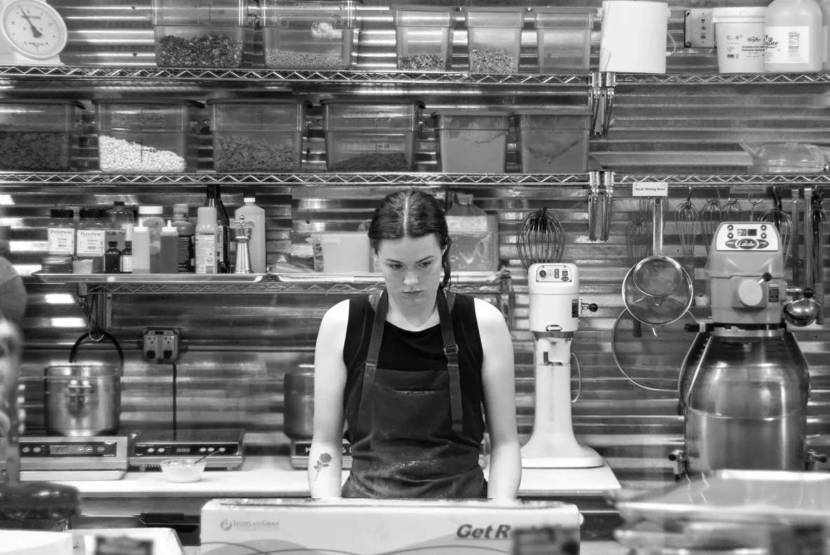 A quick-service restaurant worker at a busy back-of-house prep station