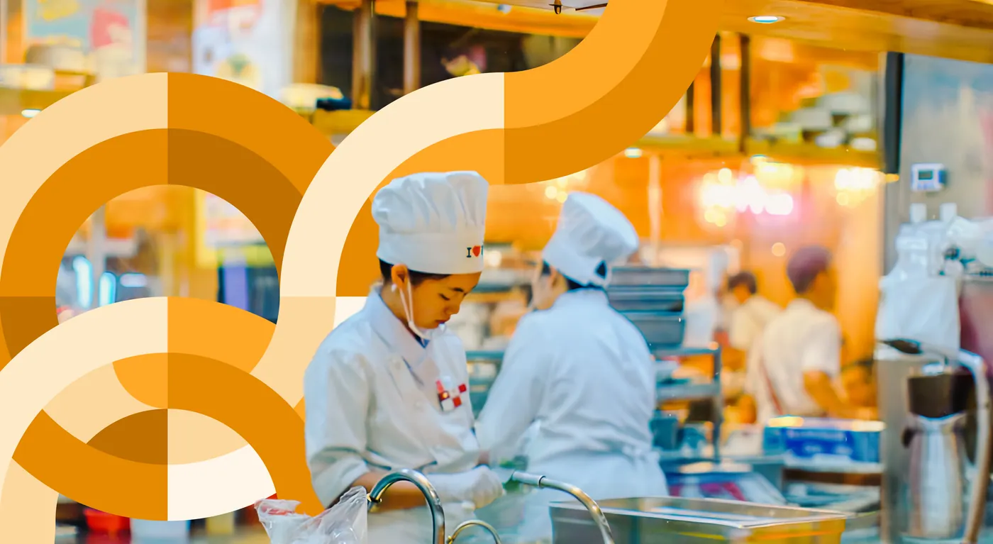 Chefs preparing food in a busy restaurant kitchen amid amber circular brand graphics