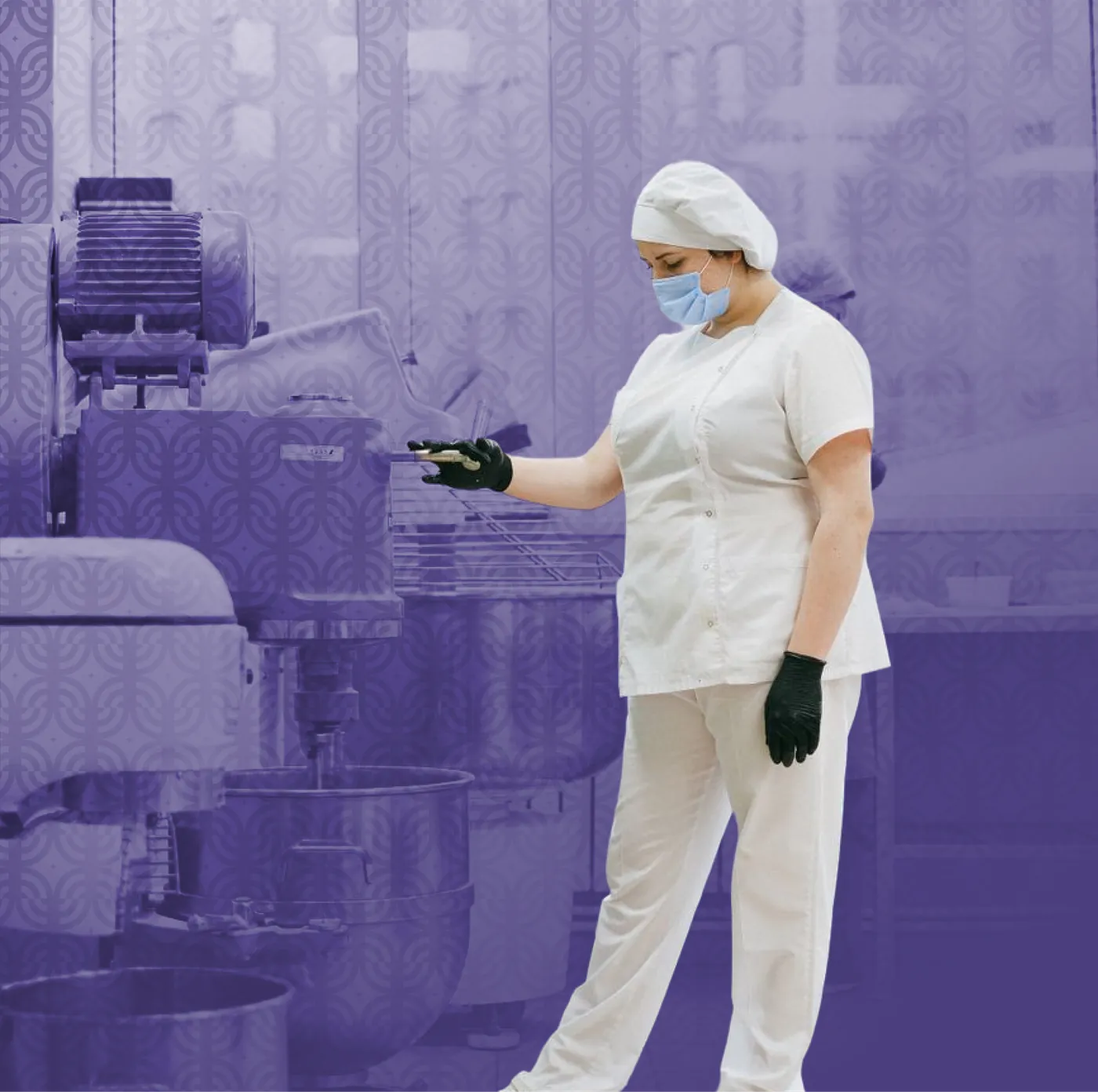 A worker in protective gear washing down kitchen equipment, in purple duotone