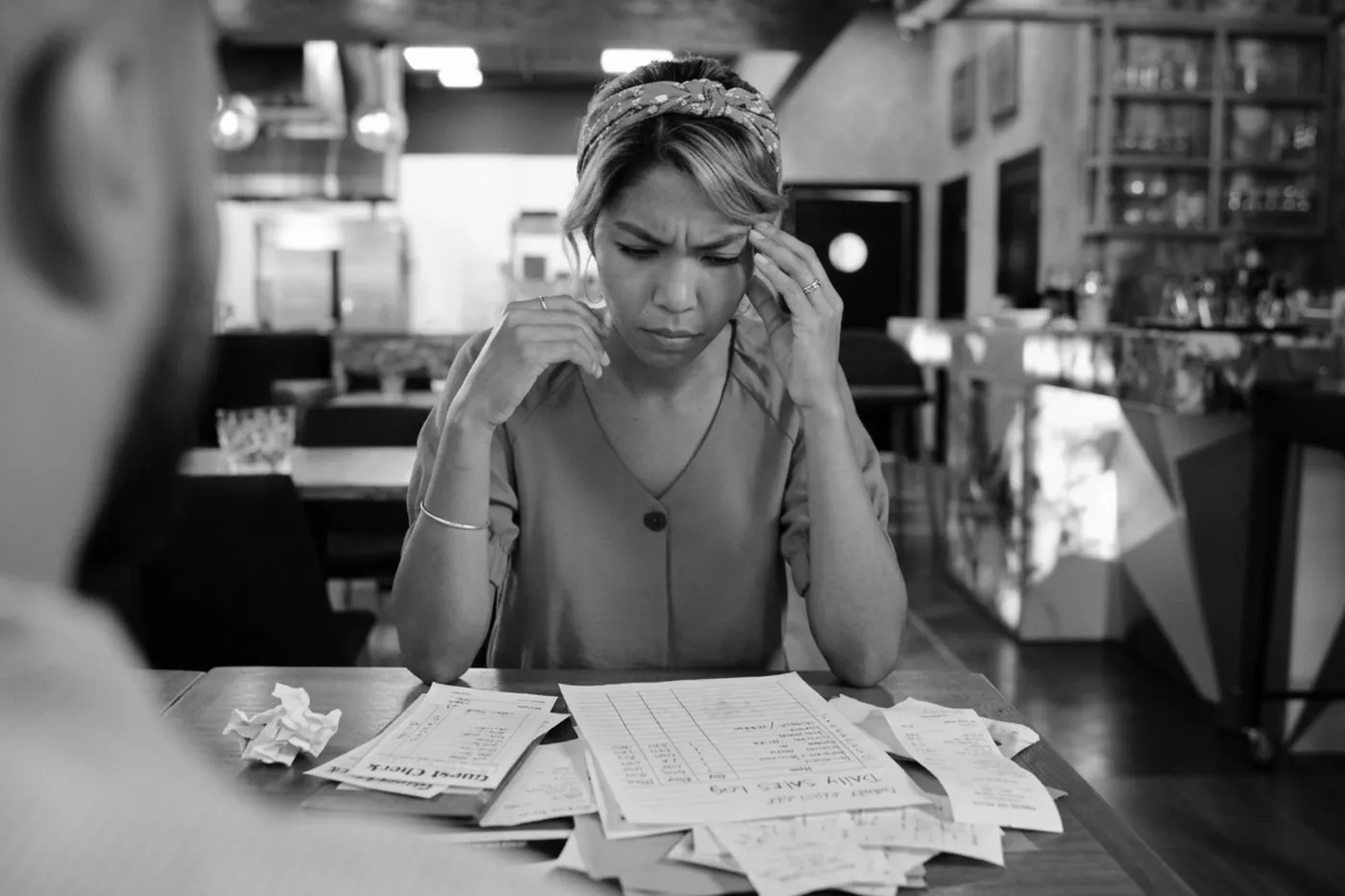 A regional manager surrounded by scattered paperwork at a table, in black and white