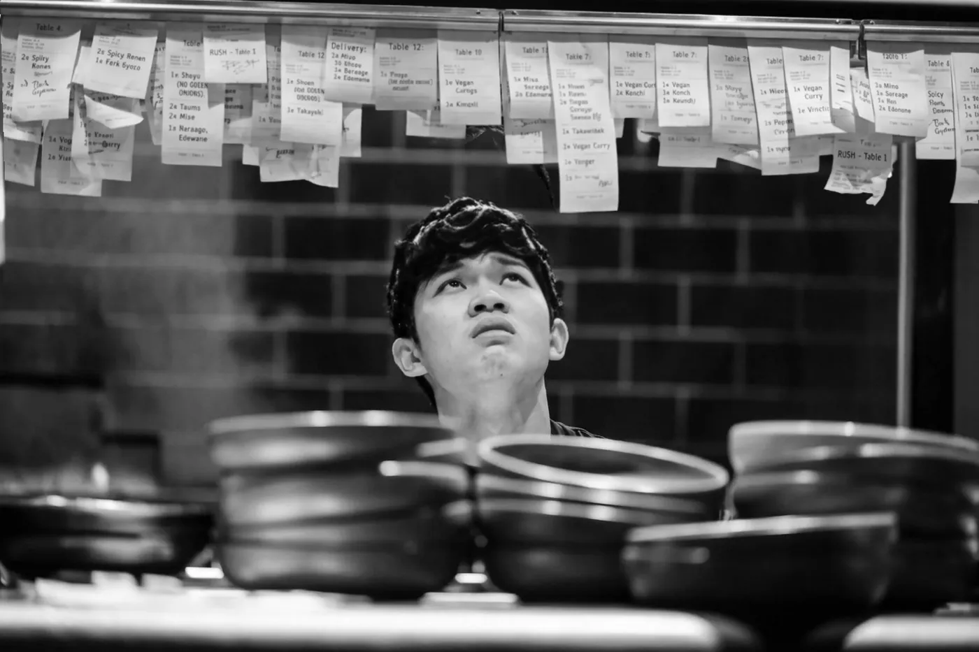 A sushi chef at work in a back-of-house kitchen, in black and white