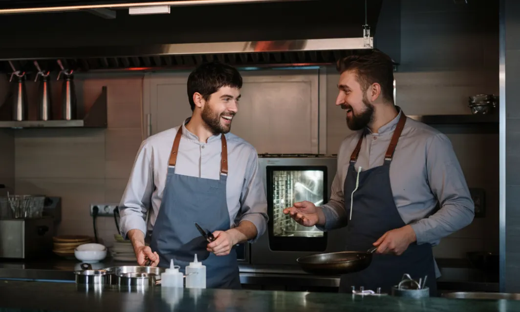 Two cooks at a kitchen line reviewing a tablet together