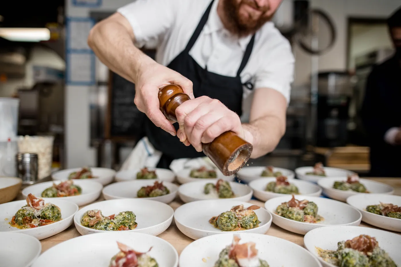 A chef garnishing plated dishes in a managed foodservice kitchen