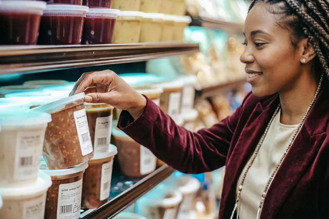 A shopper selecting a fresh grab-and-go item from a convenience-store shelf