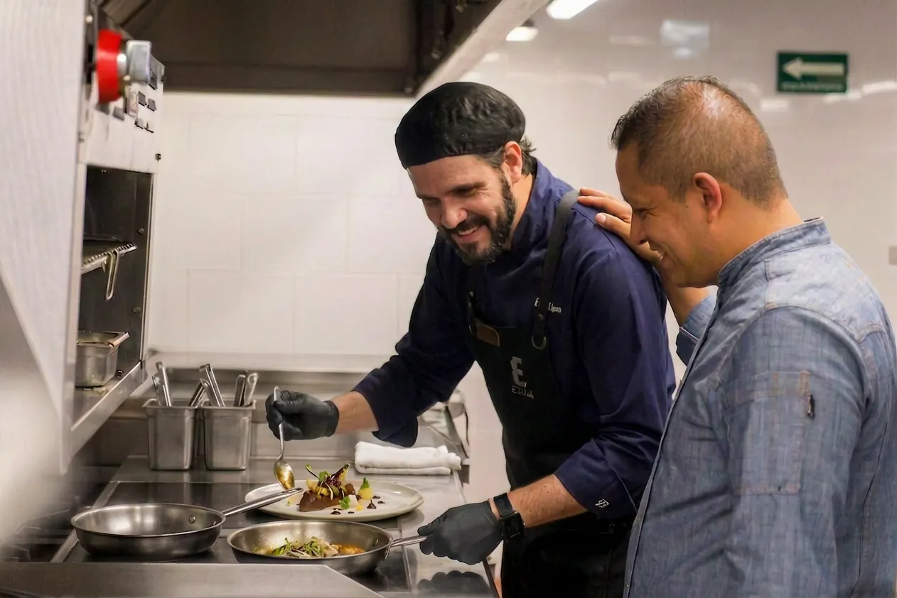 Two kitchen team members preparing food together at an organized back-of-house line