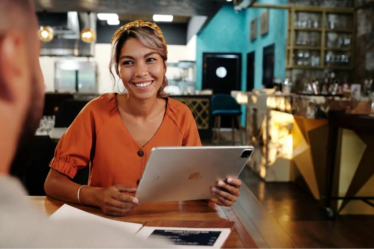 A smiling regional manager reviewing store operations on a tablet in a restaurant