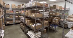 Wire shelving units in a commercial kitchen storage room holding a variety of boxed and packaged food items
